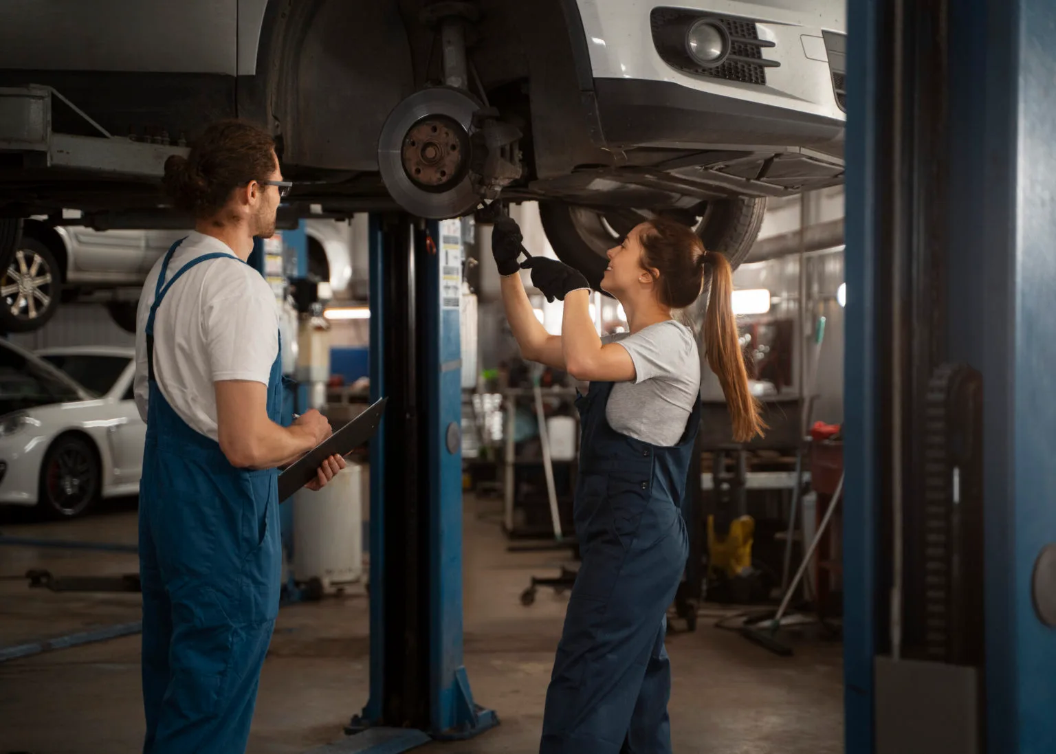 Male and female mechanics working in auto shop